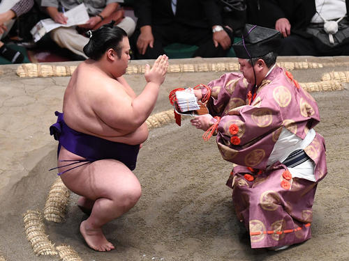 貴景勝（左）は押し出しで竜電を下し、懸賞金の束を受け取る（撮影・加藤諒）