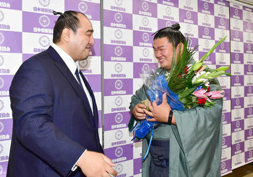 引退会見を行った誉富士（右）は伊勢ケ浜部屋の先輩の安治川親方（元安美錦）から花束贈呈を受けて笑顔を見せる（撮影・小沢裕）