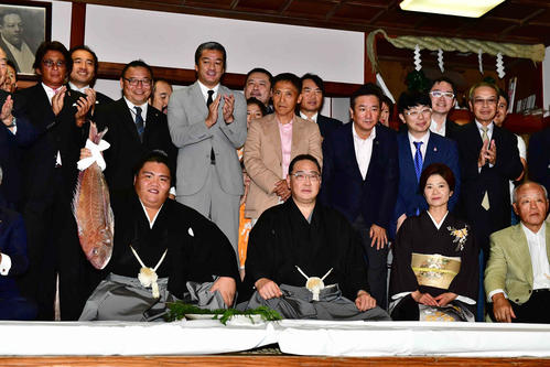 関係者に囲まれながらタイ持ちする御嶽海（左）。右へ出羽海親方、麻弓夫人（撮影・小沢裕）