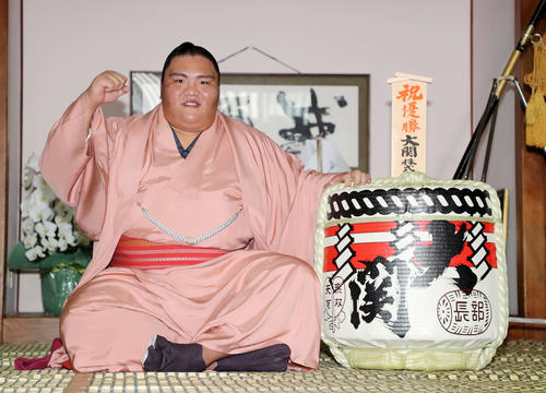 一夜明け会見で笑顔で清酒大関の酒樽を横にガッツポーズする御嶽海（撮影・鈴木正人）