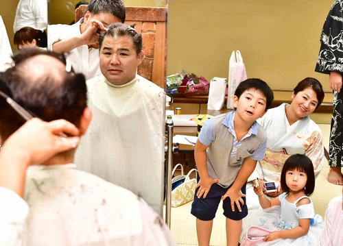 断髪式を終えた里山改め佐ノ山親方（左）は、（右へ）長男瑛太くん、長女さくらちゃん、美菜夫人ら家族から心配そうに見守られながら整髪する（撮影・小沢裕）