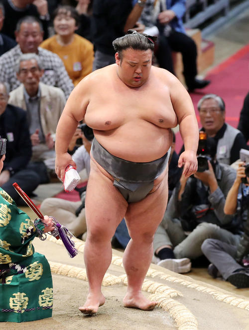 懸賞金の束を手に土俵を引き揚げる貴景勝(撮影・鈴木正人)