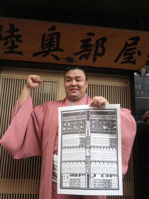 新入幕を決め番付表を手にガッツポーズする霧馬山