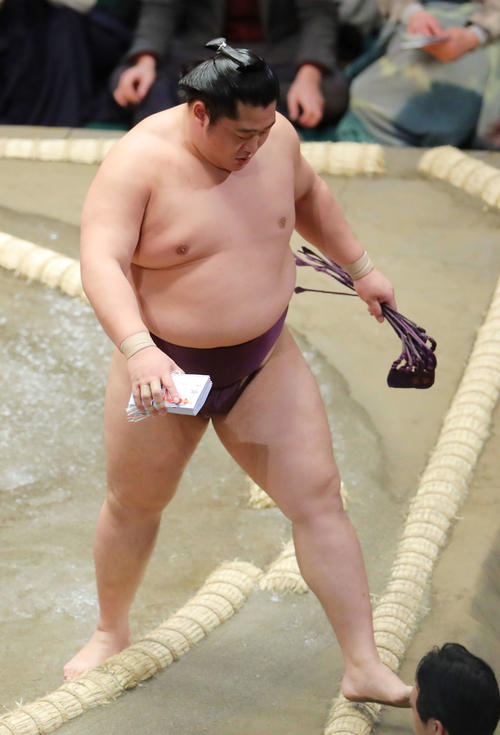 豪栄道を破り、懸賞金の束を手に土俵から引き揚げる遠藤（撮影・河田真司）