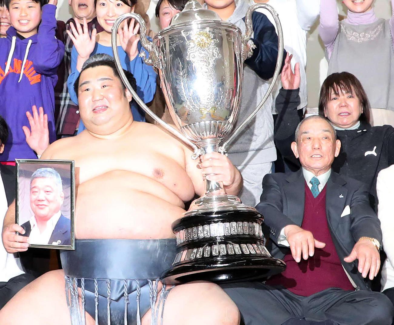 近大相撲部伊東勝人監督の遺影を手にバンザイする徳勝龍、前から2列目右は母の青木えみ子さん（撮影・鈴木正人）