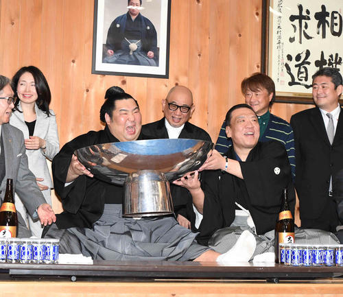 初優勝を飾り部屋に戻った徳勝龍は、木瀬親方(右)の力を借りながら大盃につがれたお酒を飲み、おどけた表情を見せる(撮影・小沢裕)