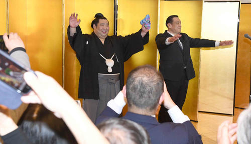 初優勝を飾った徳勝龍は祝勝会で大勢の出席者を前に万歳する。右は師匠の木瀬親方(撮影・小沢裕)