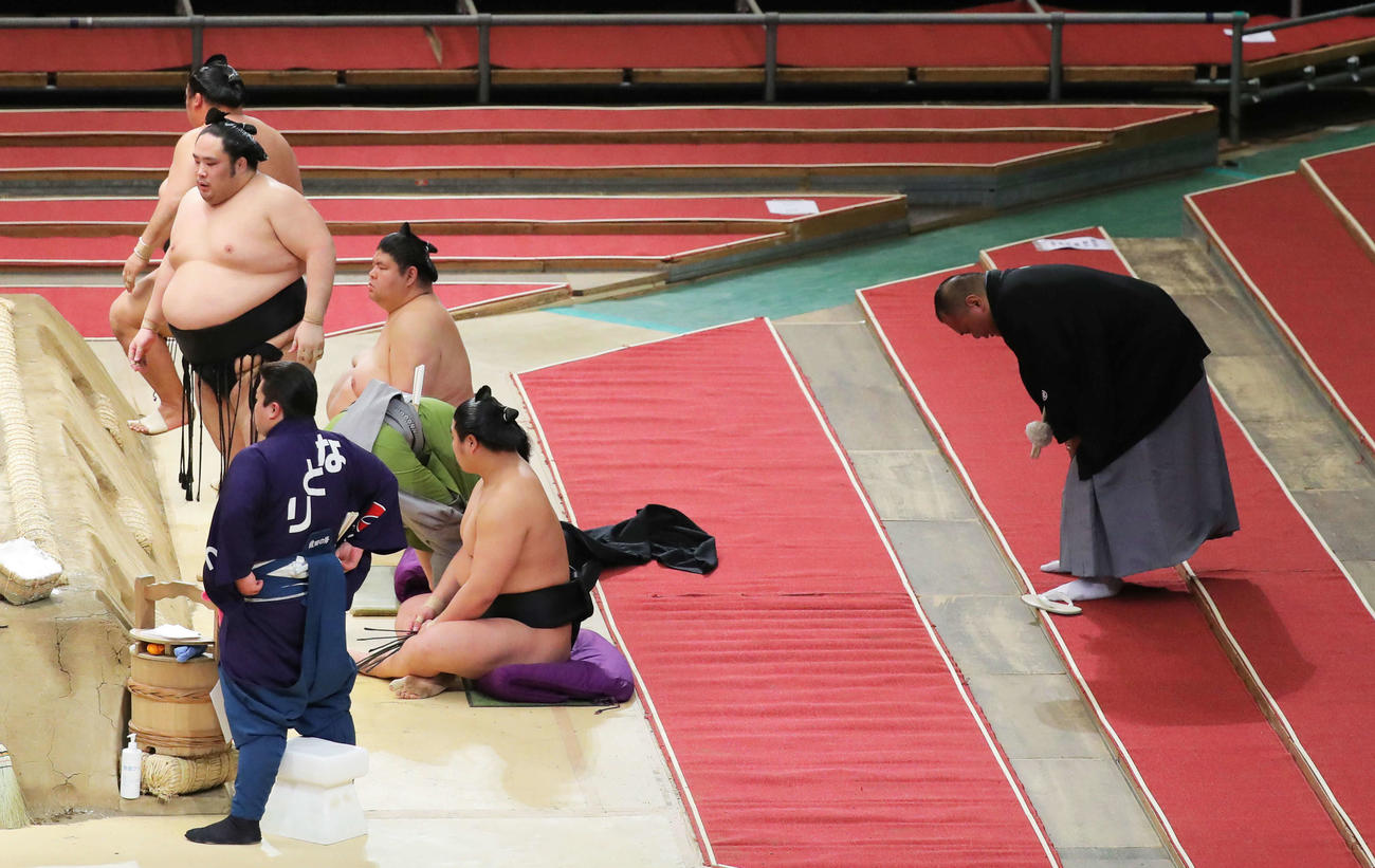 豊ノ島（左）との取組で落下した千代鳳（左から2人目）と衝突し、砂かぶり席まで下がり痛そうに体を丸める審判の浦風親方（右）（撮影・河田真司）