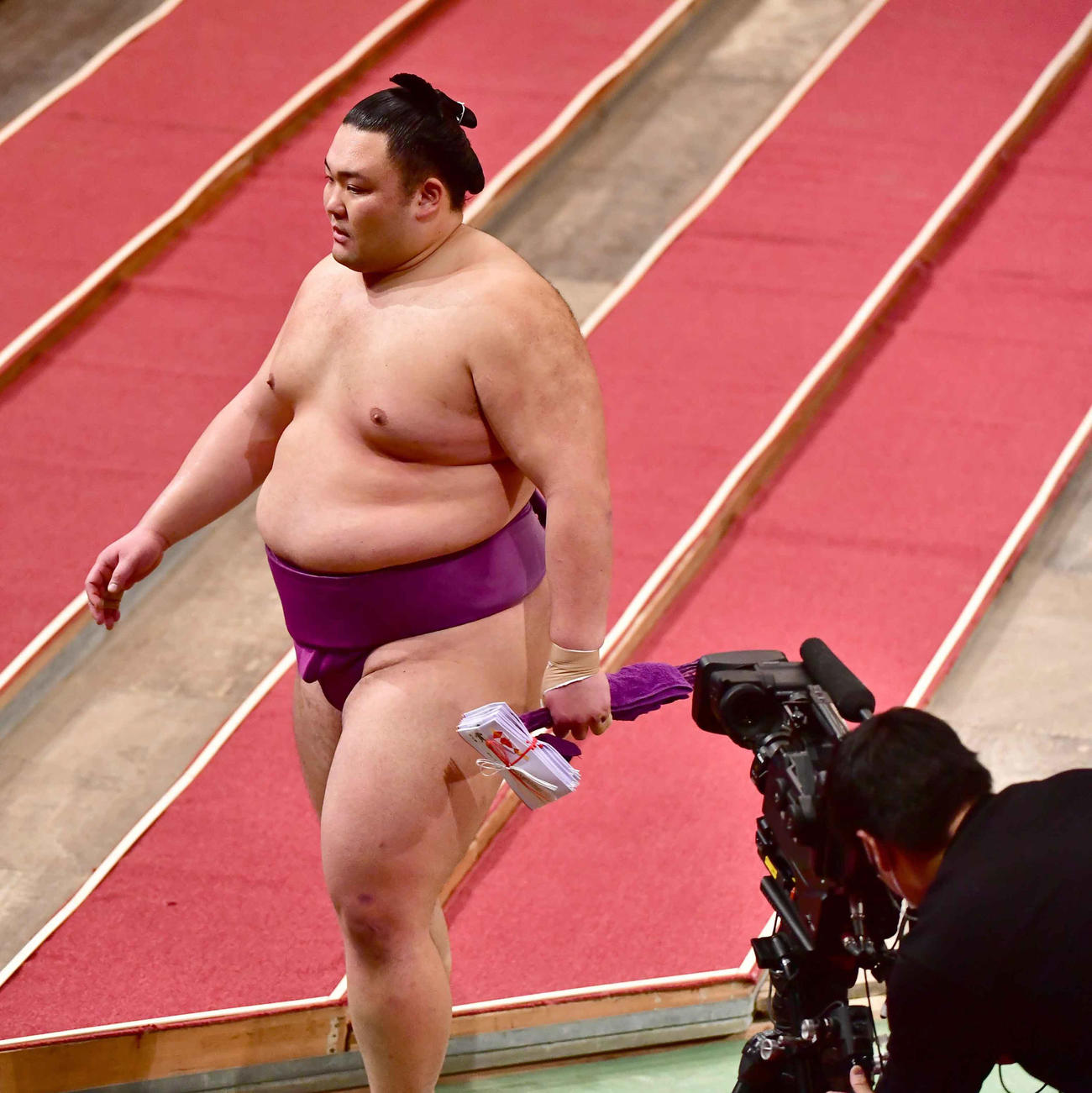 2敗を死守し白星を2ケタに乗せた朝乃山は懸賞を手に花道を引き揚げる（撮影・小沢裕）