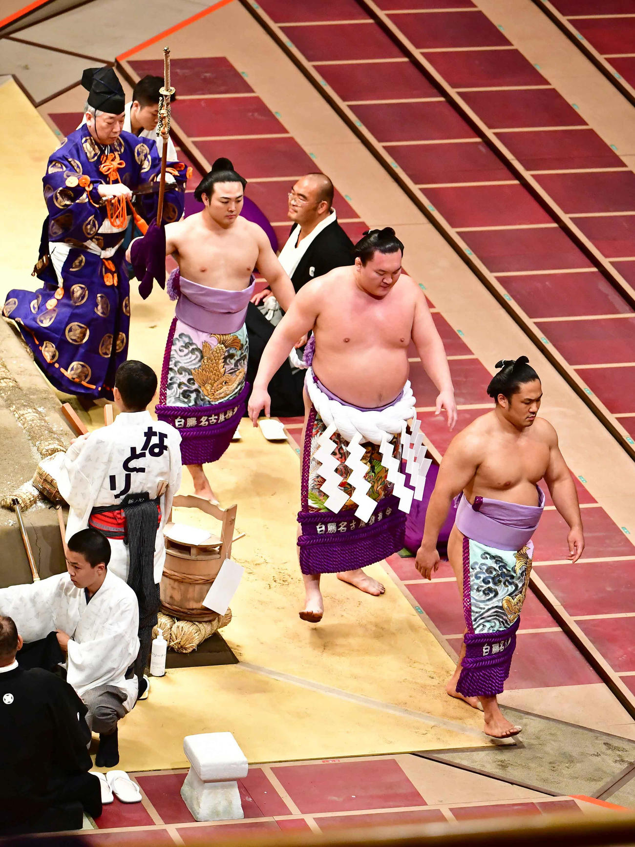 横綱土俵入りを終えた白鵬は露払いに石浦（手前右）、太刀持ちに炎鵬を従えて花道を引き揚げる（撮影・小沢裕）