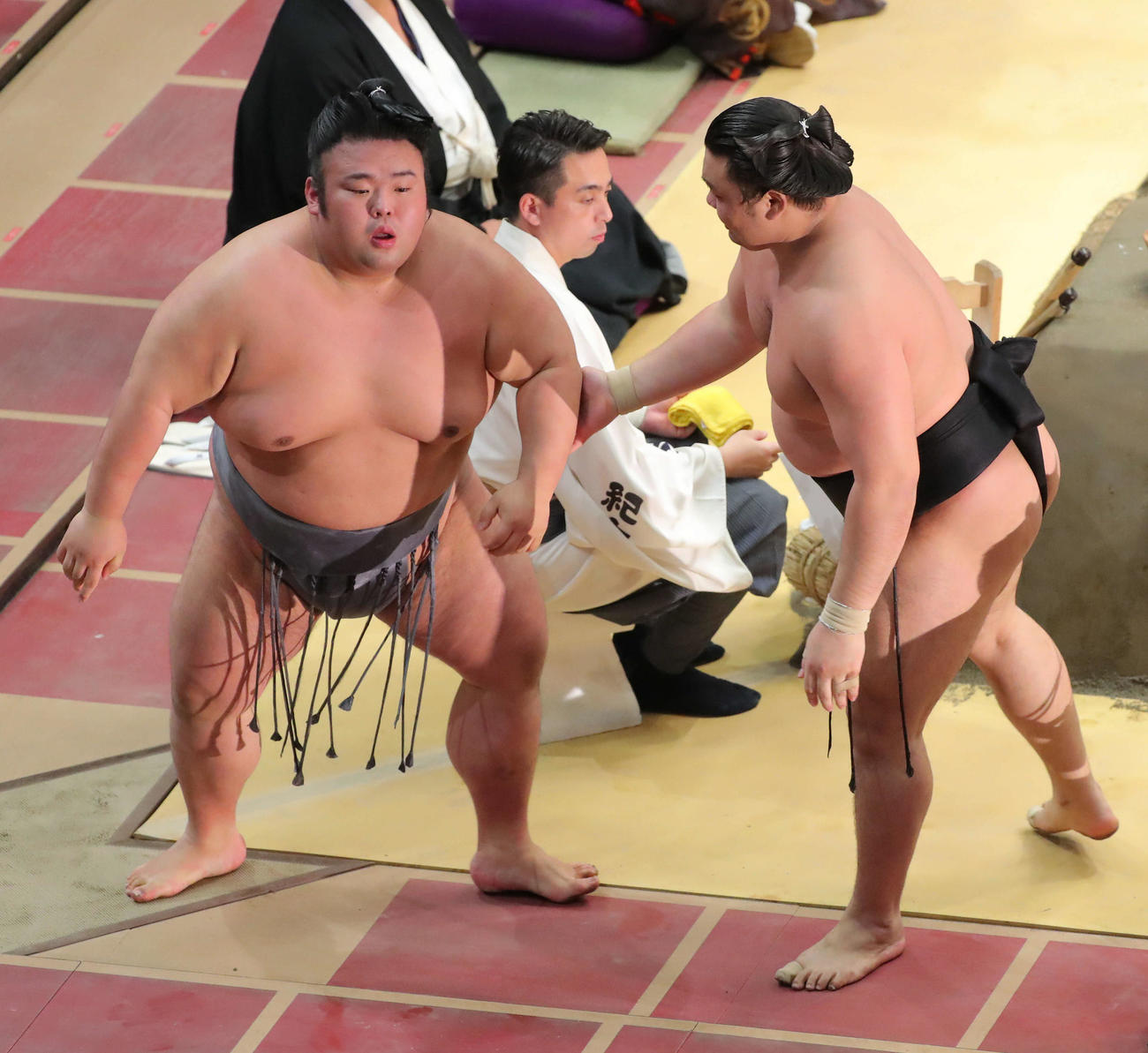 寄り切りで敗れた貴景勝（左）を、土俵から降り手を持ち起こす霧馬山（撮影・河田真司）　