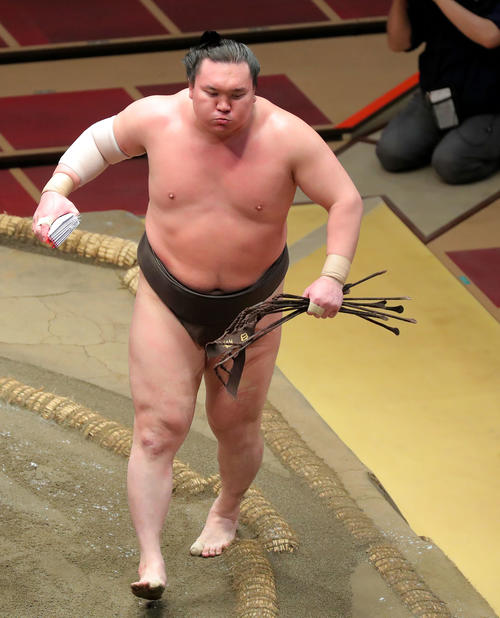 輝を下し、懸賞金の束を手に意気揚々と土俵から引き揚げる白鵬（撮影・河田真司）　　　
