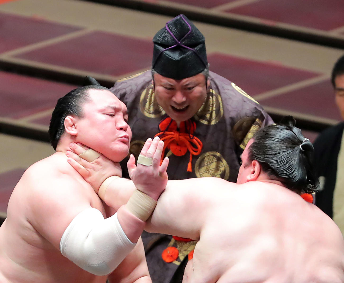 碧山（右）ののど輪に耐える白鵬。中央は行司の木村玉治郎（撮影・河田真司）　　　