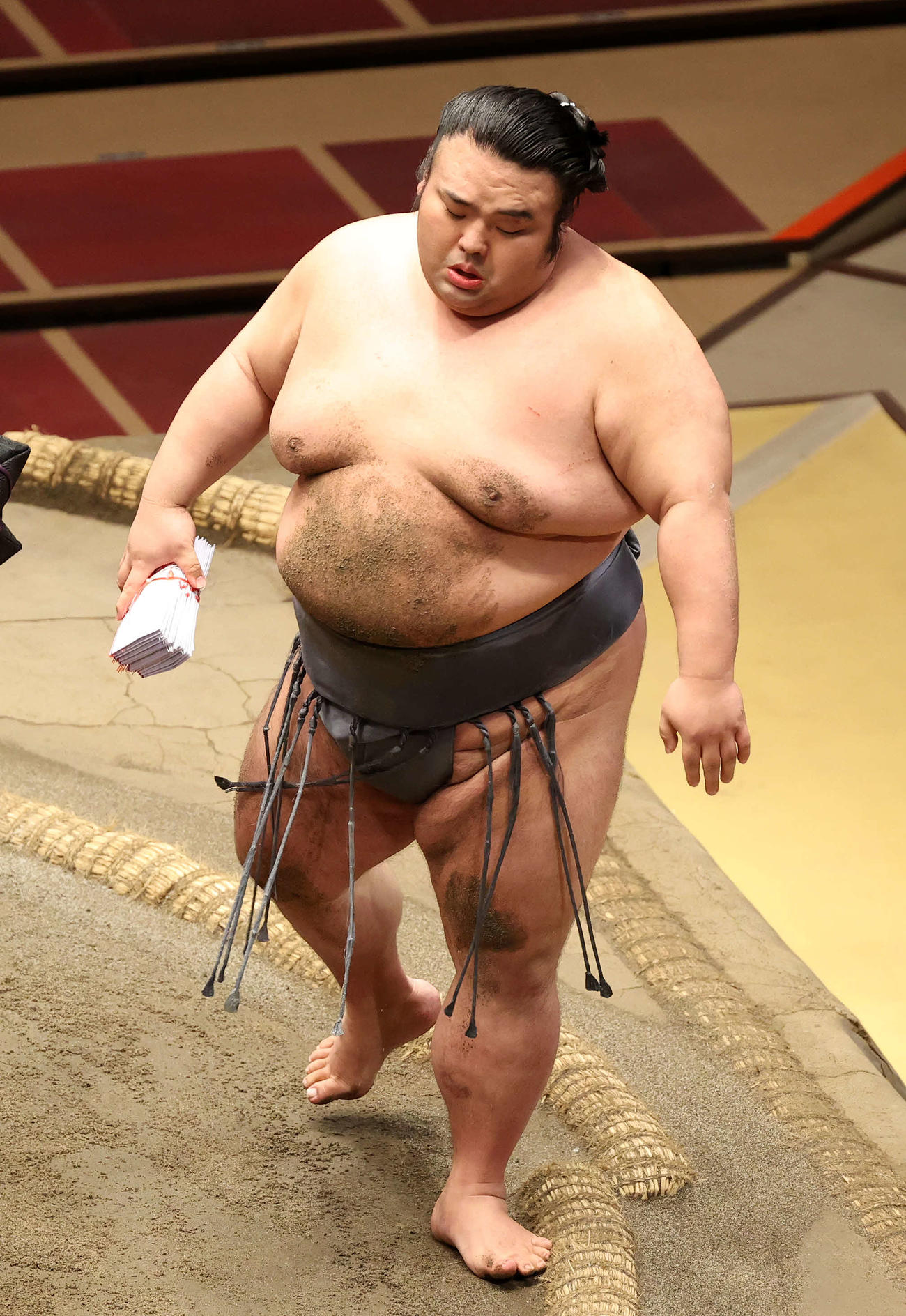 懸賞金の束を手に土俵を引き揚げる貴景勝（撮影・鈴木正人）