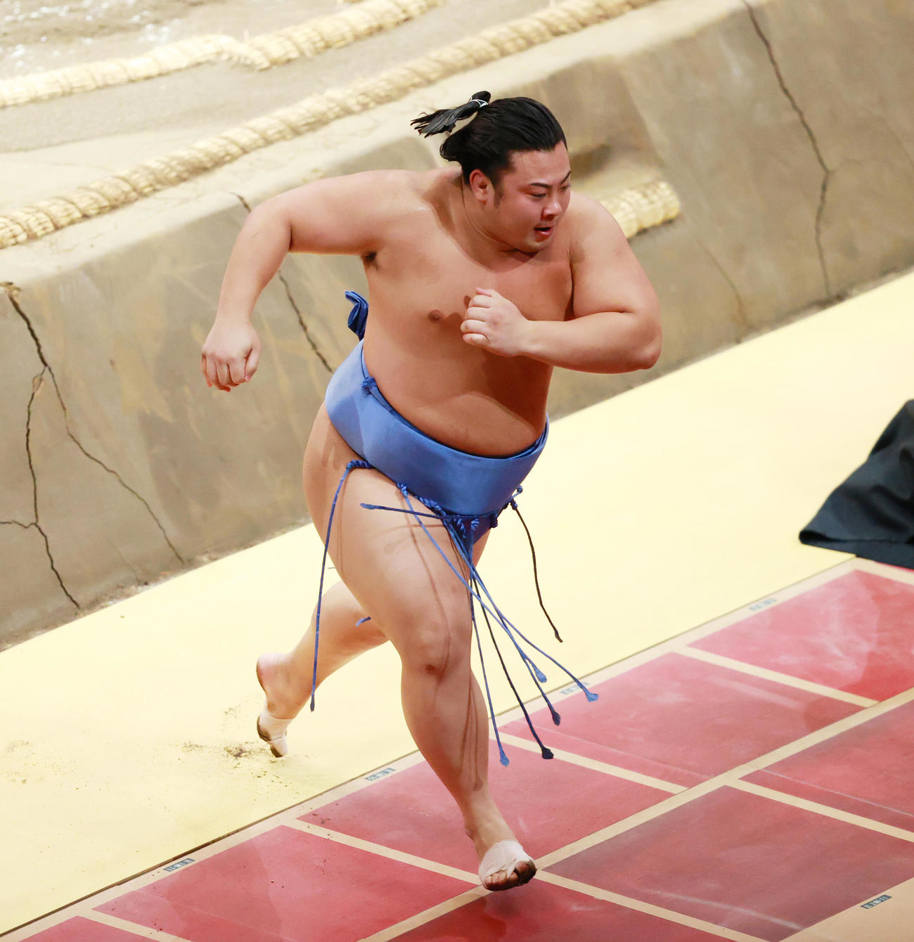 明生を押し出しで破り勢い余って空席を走り抜ける翔猿（撮影・中島郁夫）