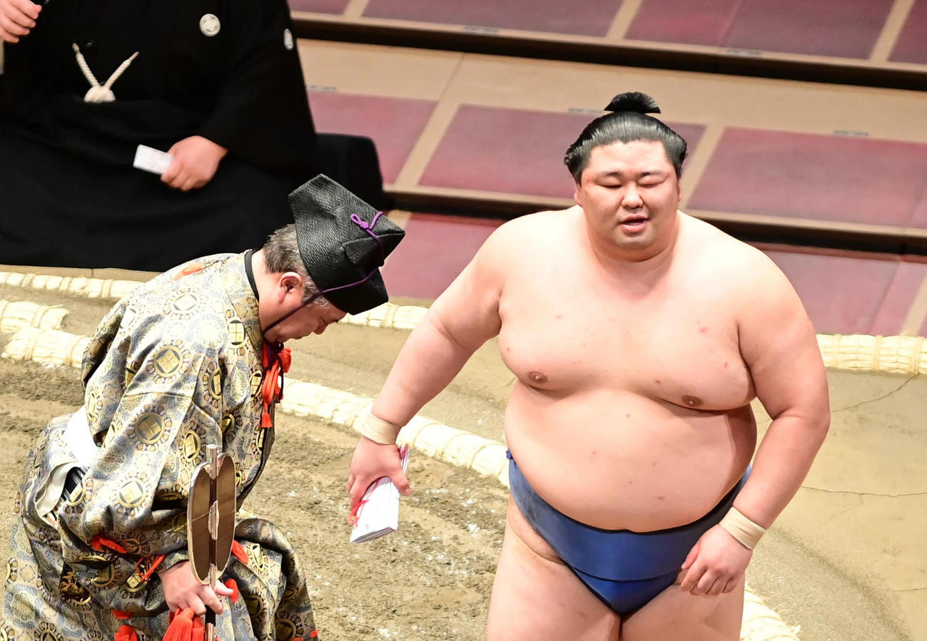 初日を白星で飾った正代（右）は懸賞の束を手にホっとした表情を見せる（撮影・小沢裕）