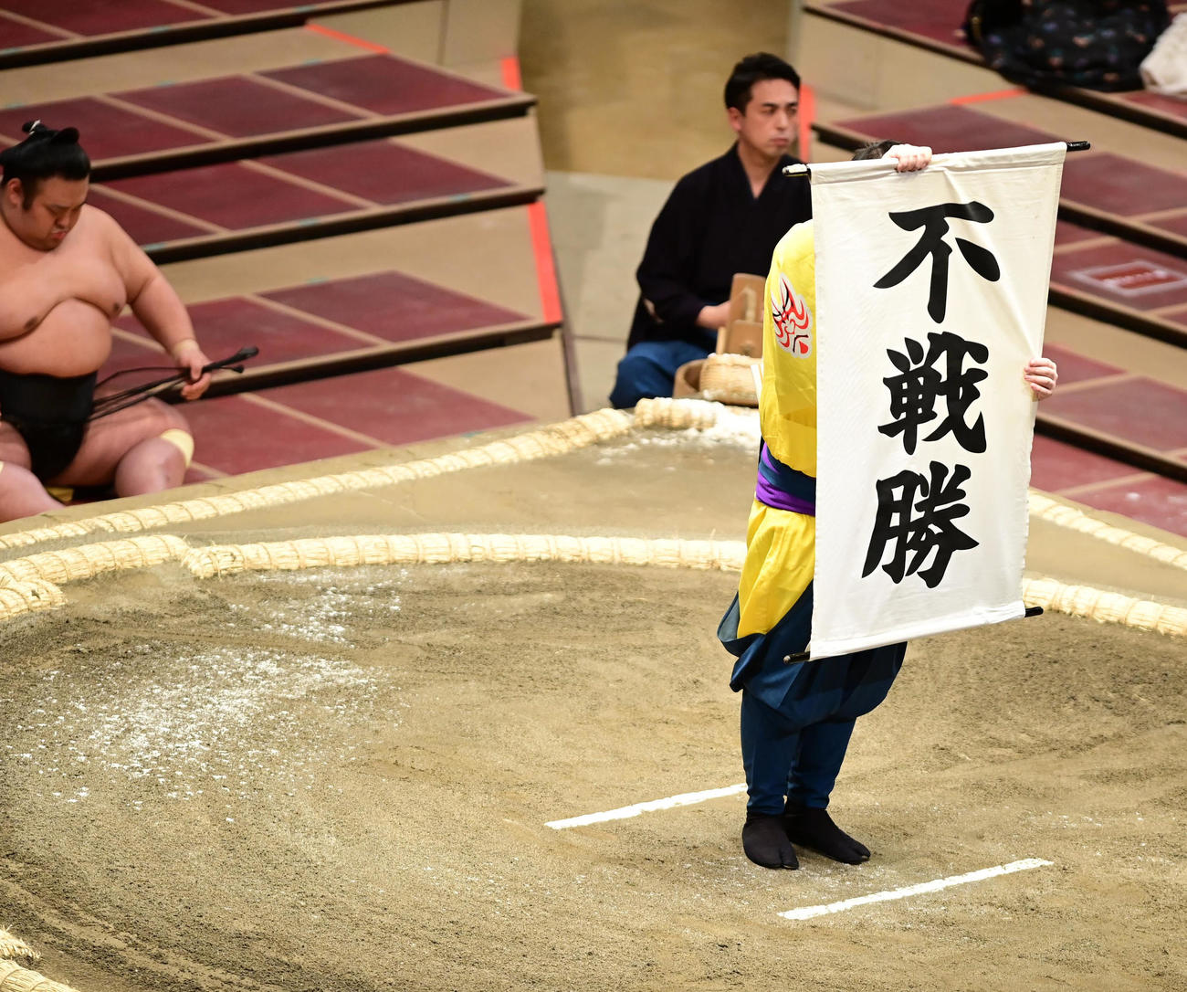 朝乃山の休場により若隆景の不戦勝を告げる幕が場内に掲げられる。左は貴景勝（撮影・小沢裕）