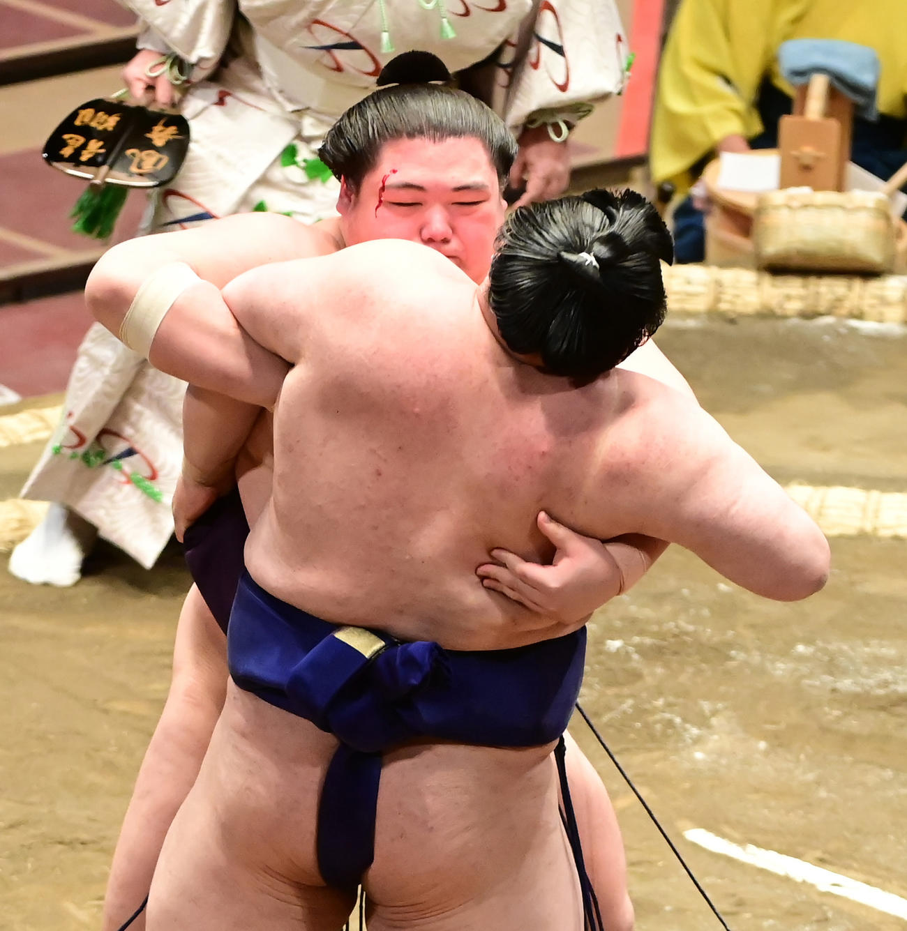 王鵬（左）は右目の辺りを流血しながら貴源治を寄り切りで破り初日を出した（撮影・小沢裕）
