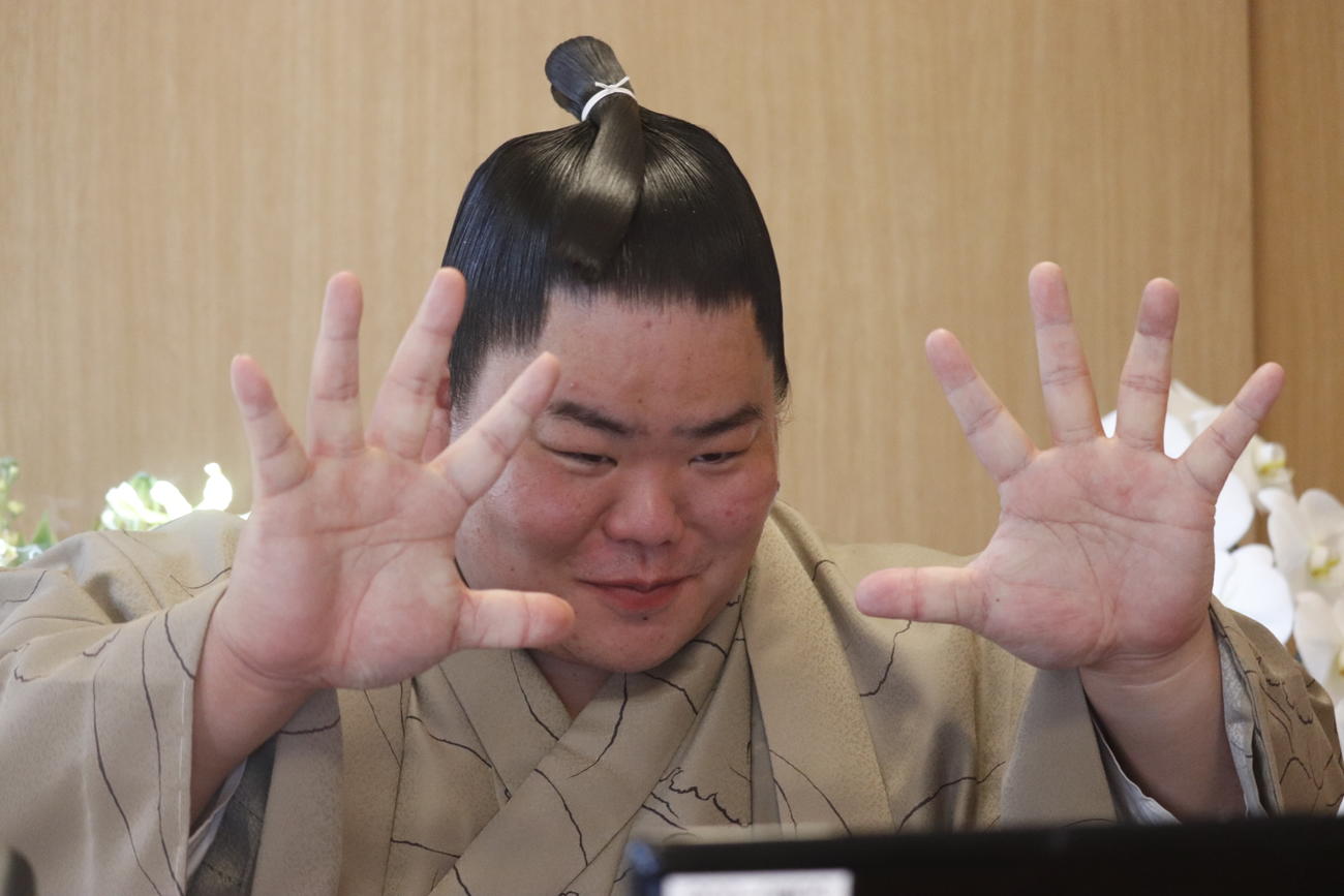 初優勝した初場所から一夜明け、リモートでの会見に出席して自慢の大きな手を画面越しの報道陣に見せる大栄翔（日本相撲協会提供）