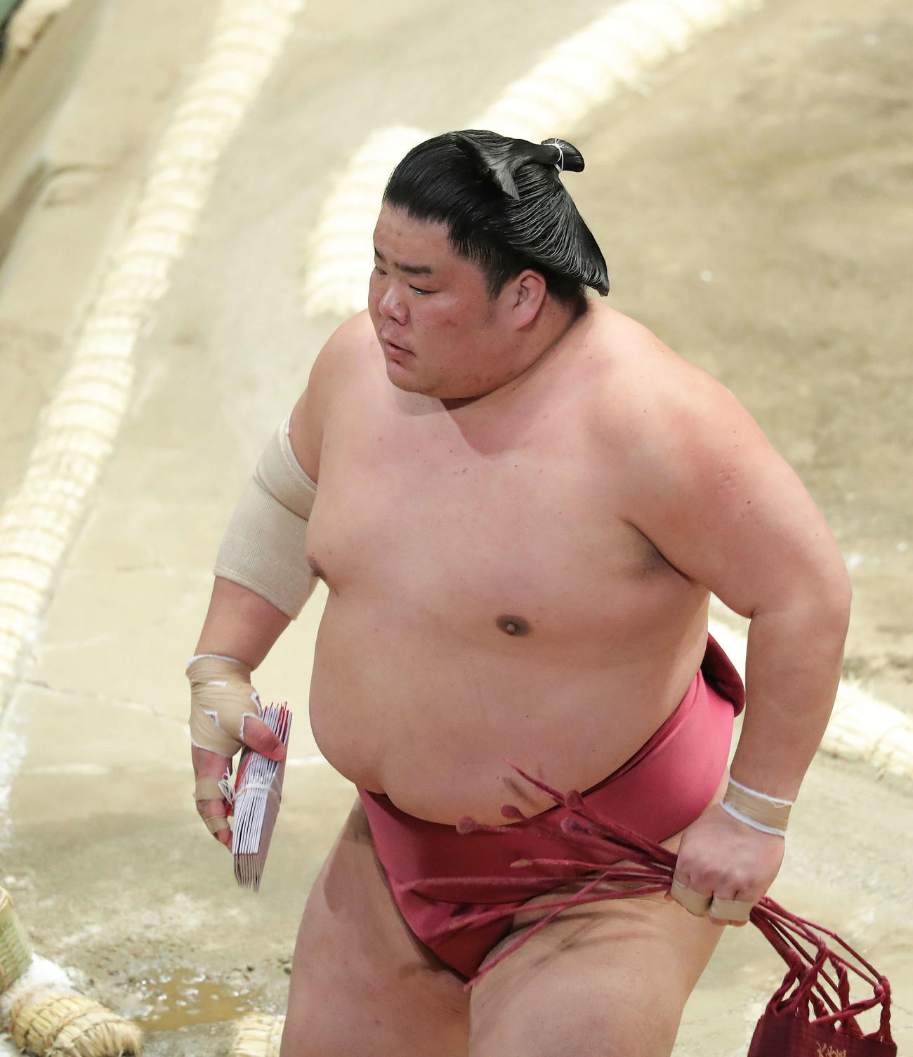 御嶽海を押し出しで破り、懸賞金の束を手に土俵から引き揚げる大栄翔（撮影・河田真司）