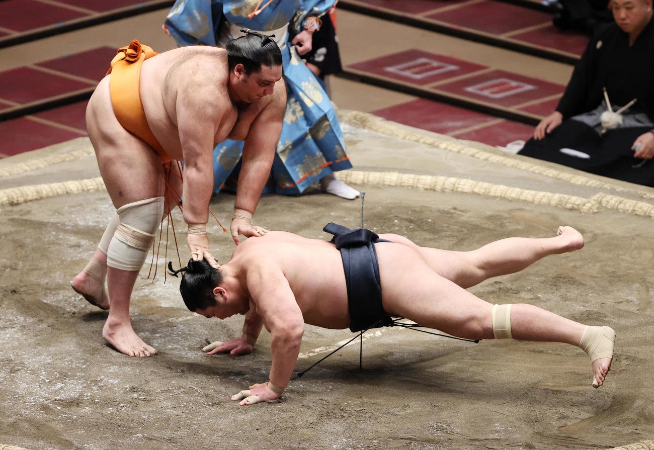 輝（右）を引き落としで破る魁聖（撮影・野上伸悟）