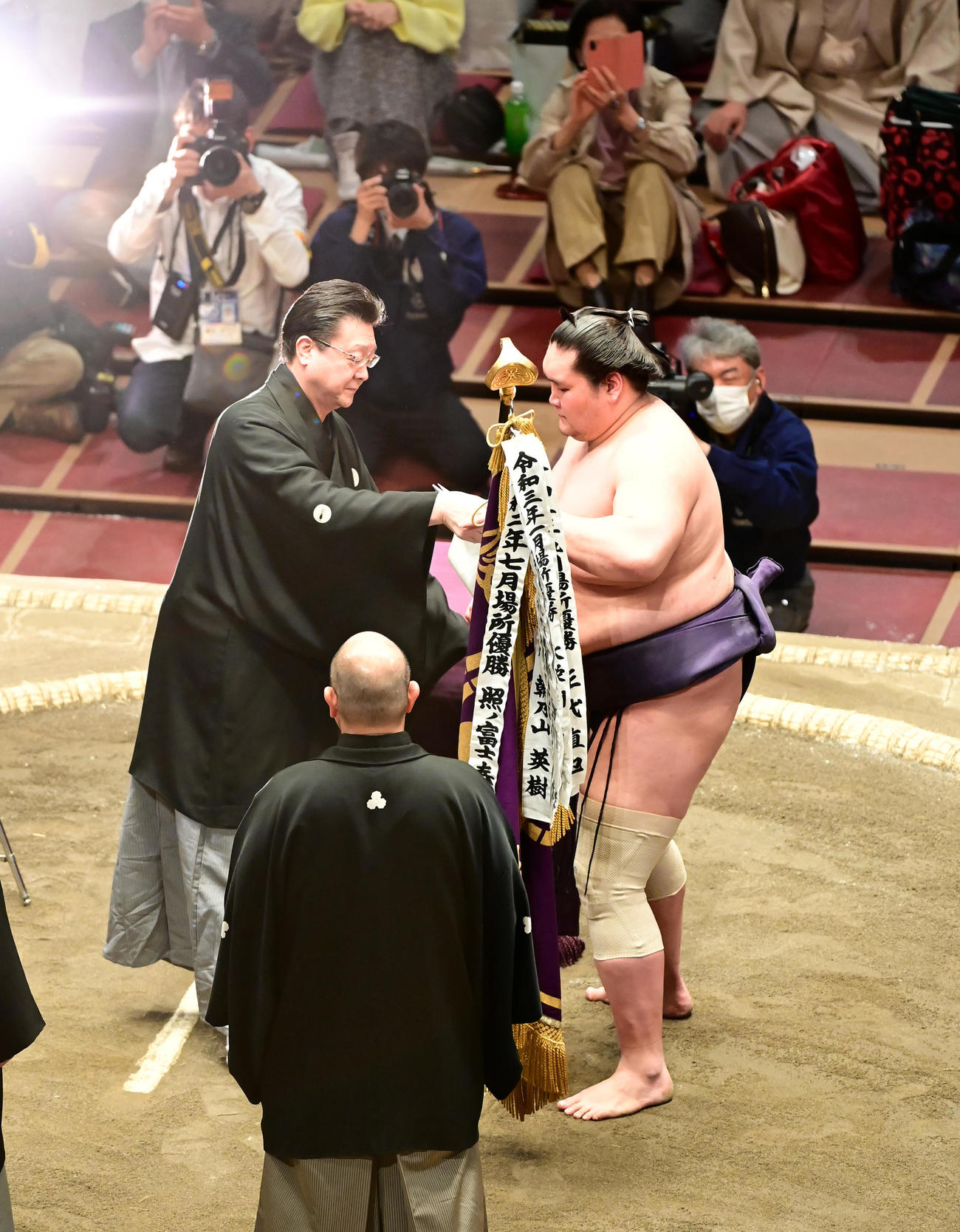 幕内優勝を飾り師匠の伊勢ケ浜審判部長（左）から優勝旗を受け取る照ノ富士（撮影・小沢裕）