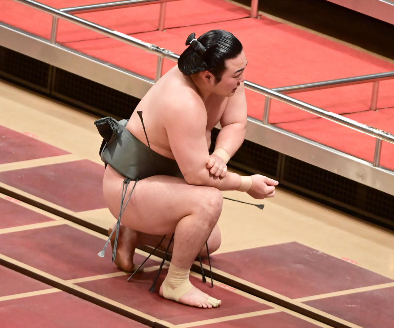 宇良にきめ出しで敗れた炎鵬は無観客の館内で痛めた右腕を押さえて座り込む（撮影・小沢裕）