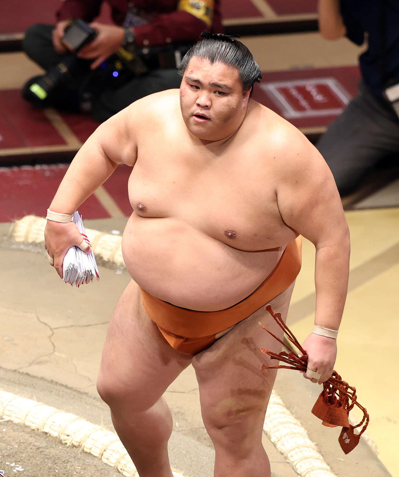 懸賞金の束を手に土俵を引き揚げる御嶽海（撮影・鈴木正人）