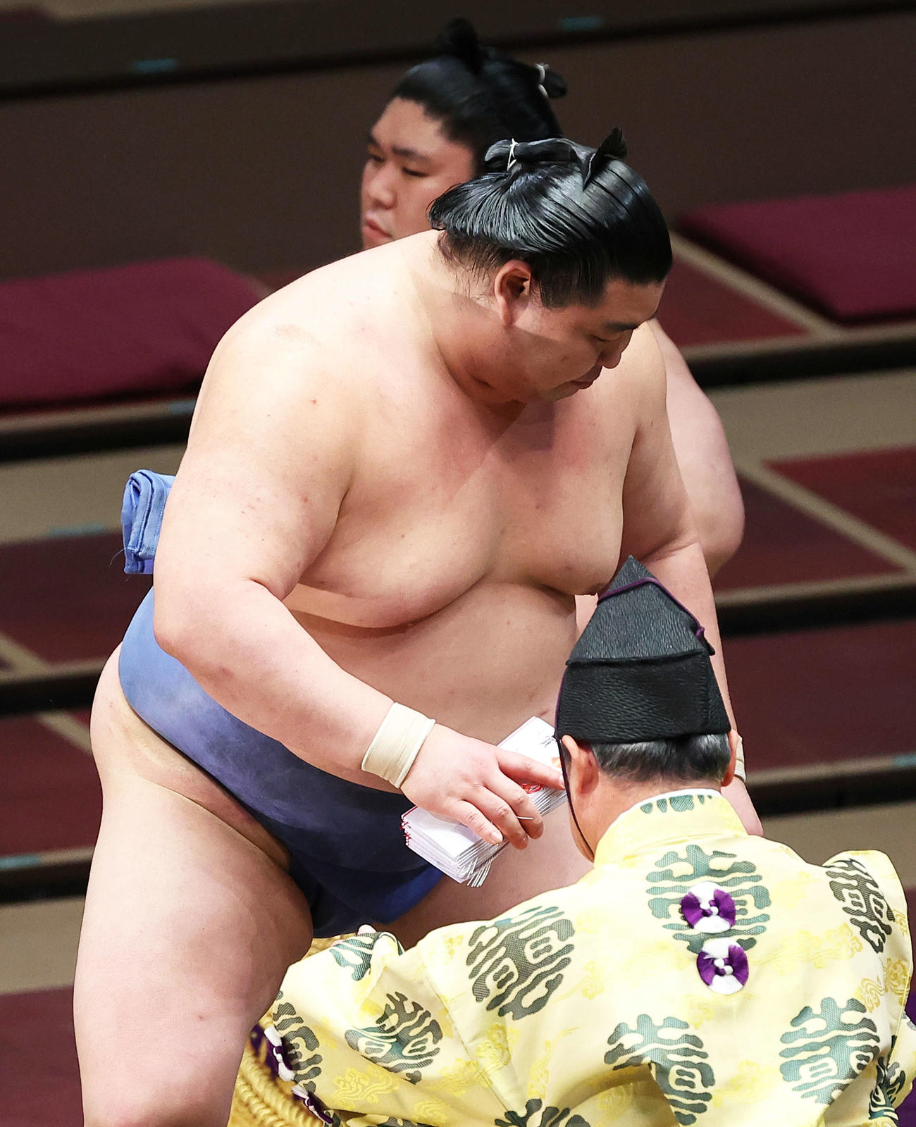 大栄翔を突き落としで破り、懸賞金の束を手に土俵から引き揚げる正代（撮影・河田真司）