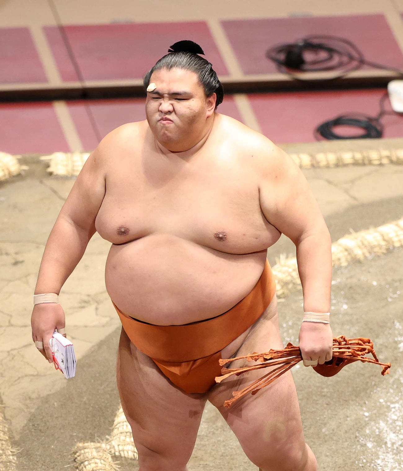 懸賞金の束を手に土俵を引き揚げる御嶽海（撮影・鈴木正人）