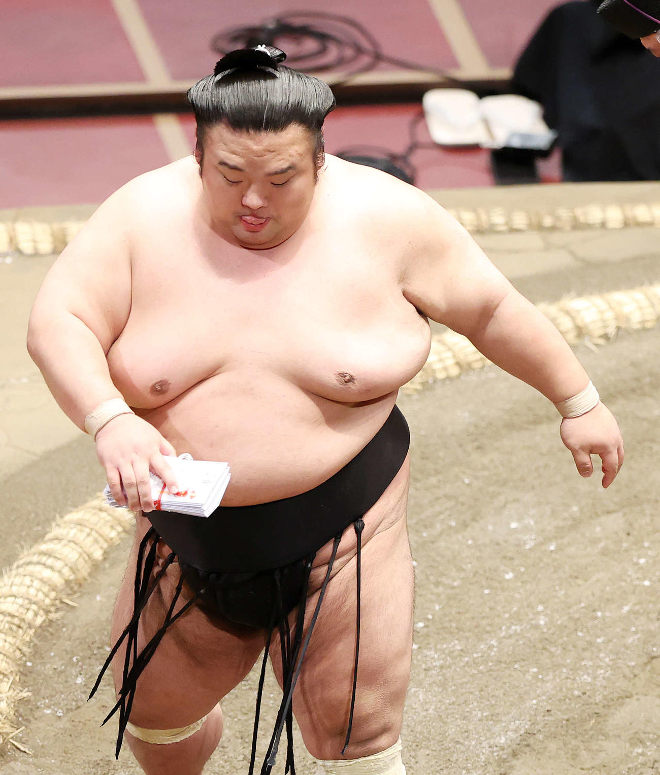懸賞金の束を手に土俵を引き揚げる貴景勝（撮影・鈴木正人）