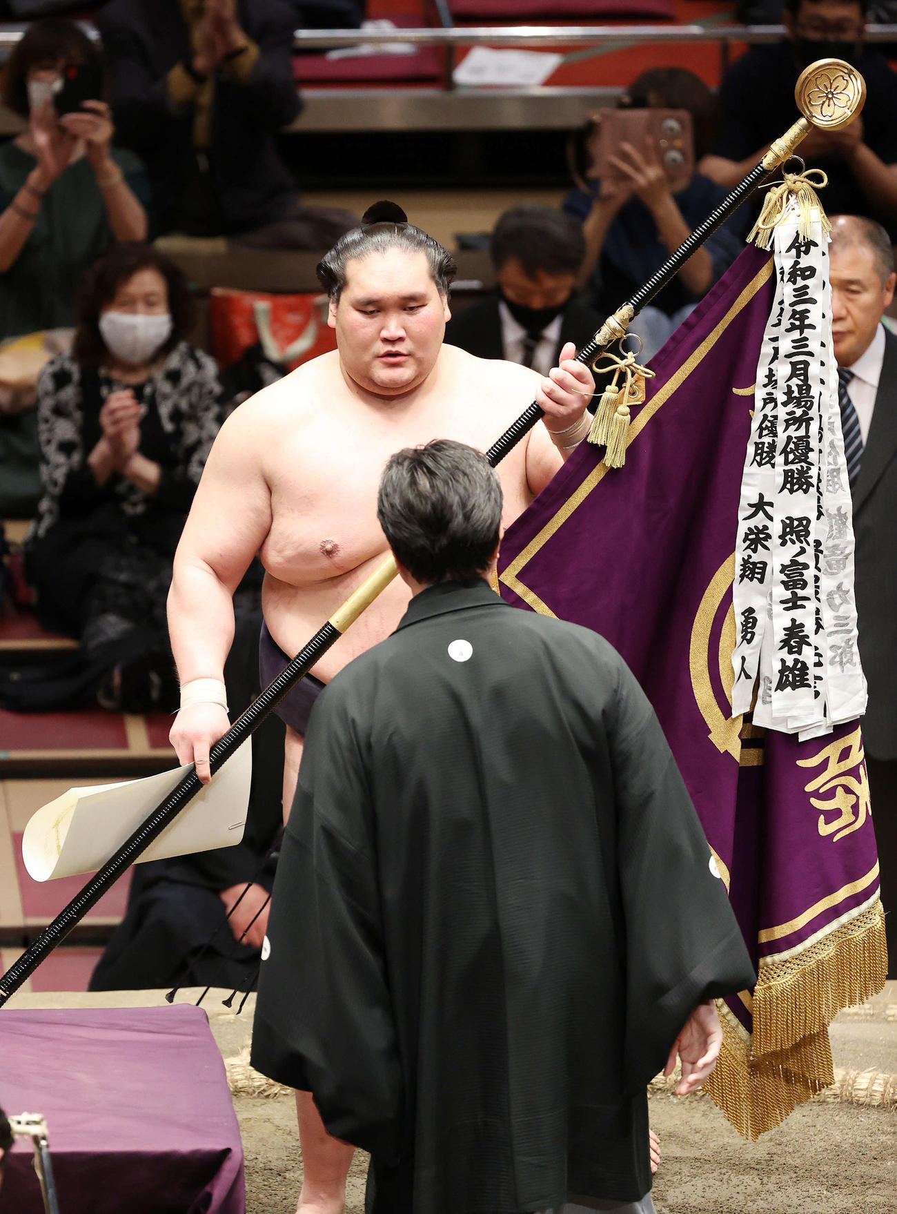 伊勢ケ浜審判部長（手前）から優勝旗を受け取る照ノ富士（撮影・鈴木正人）