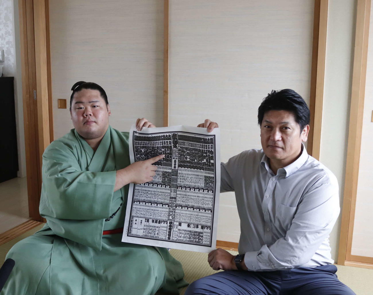 新番付表の自分の番付を指さす新小結の明生。右は師匠の立浪親方