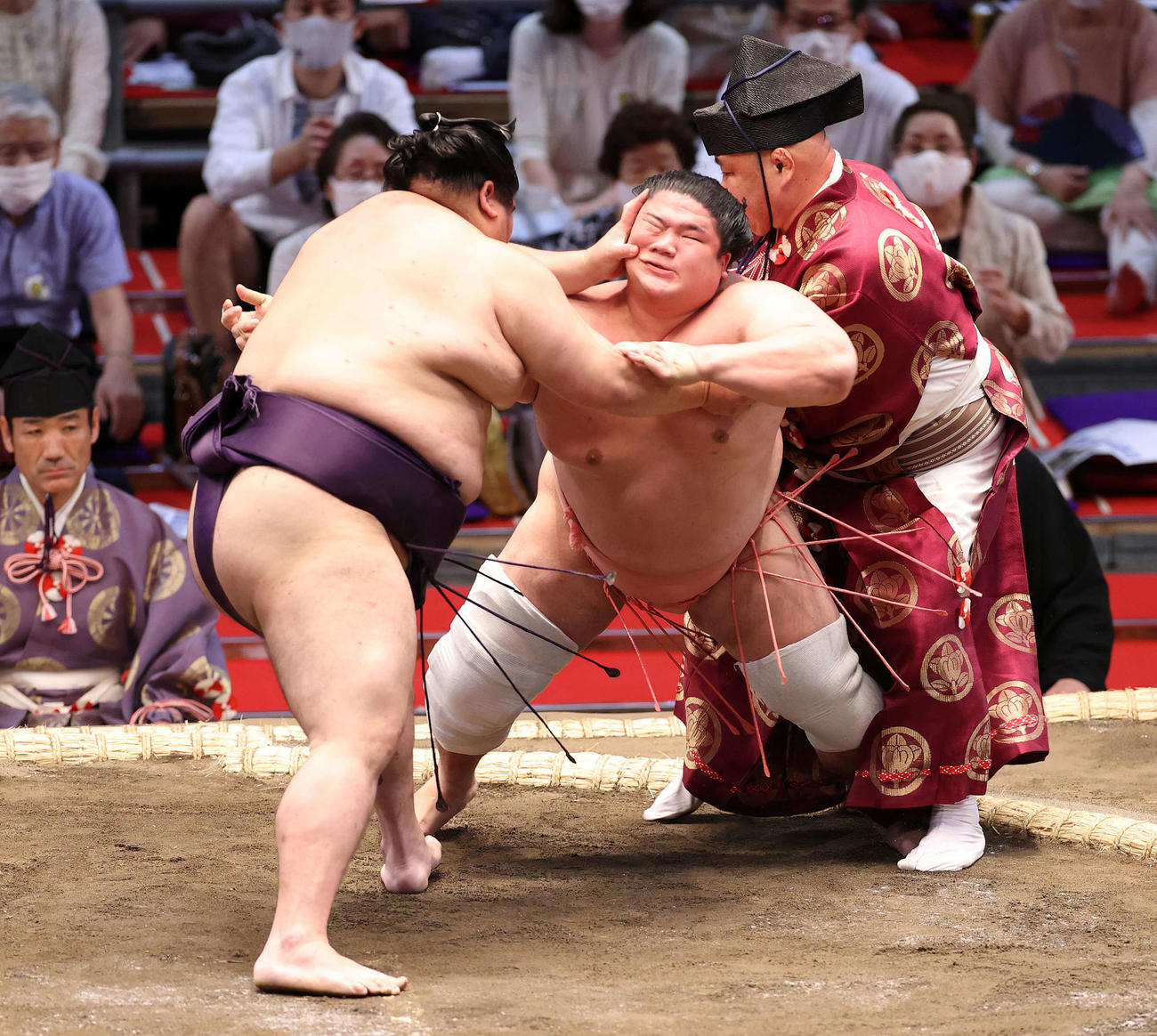 大奄美（左）の攻めに耐える宇良は行司の木村秋治郎とぶつかる（撮影・鈴木正人）
