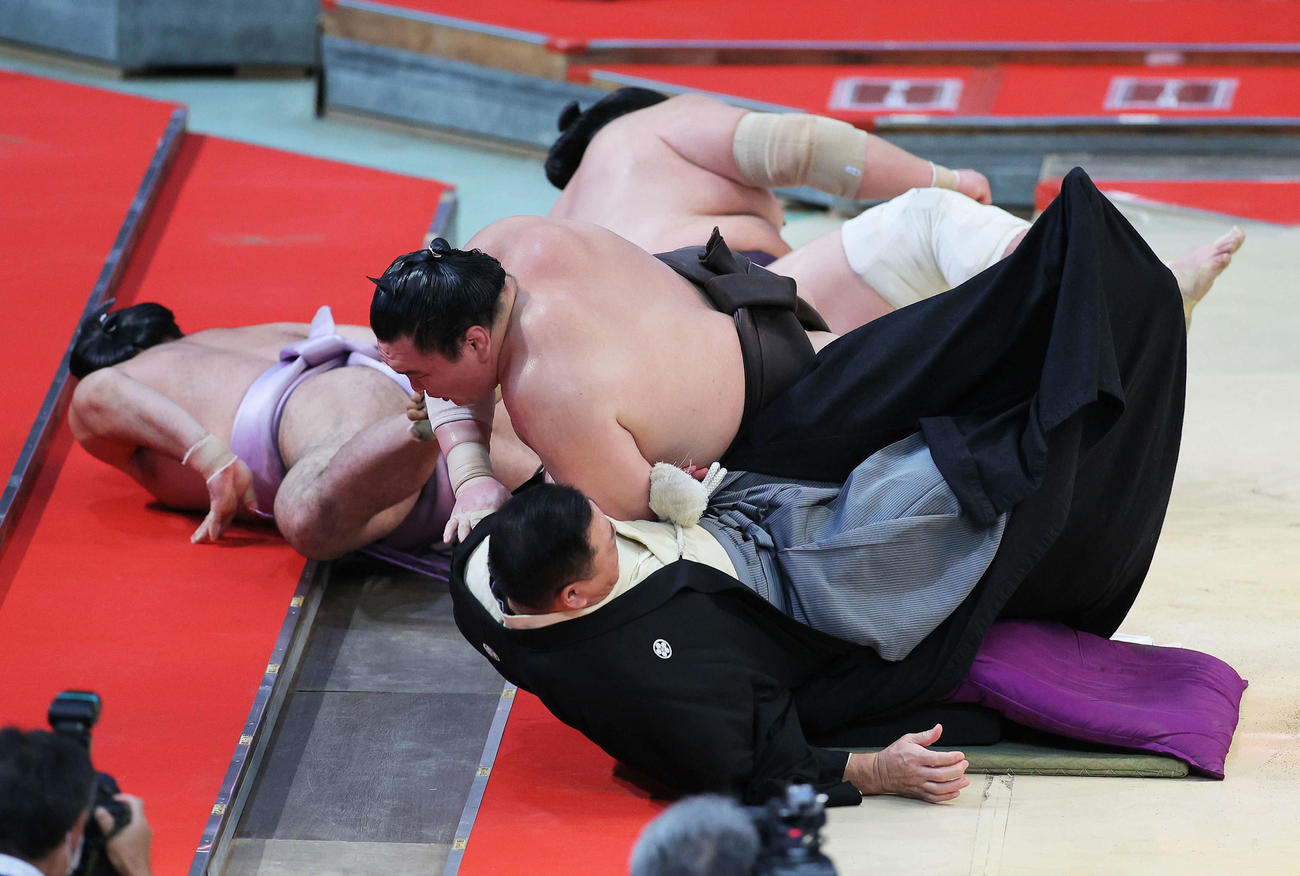琴恵光（左）を寄り切りで下し、勢い余り土俵から落ちる白鵬（中央）は枝川親方にぶつかる。奥は照ノ富士（撮影・河田真司）