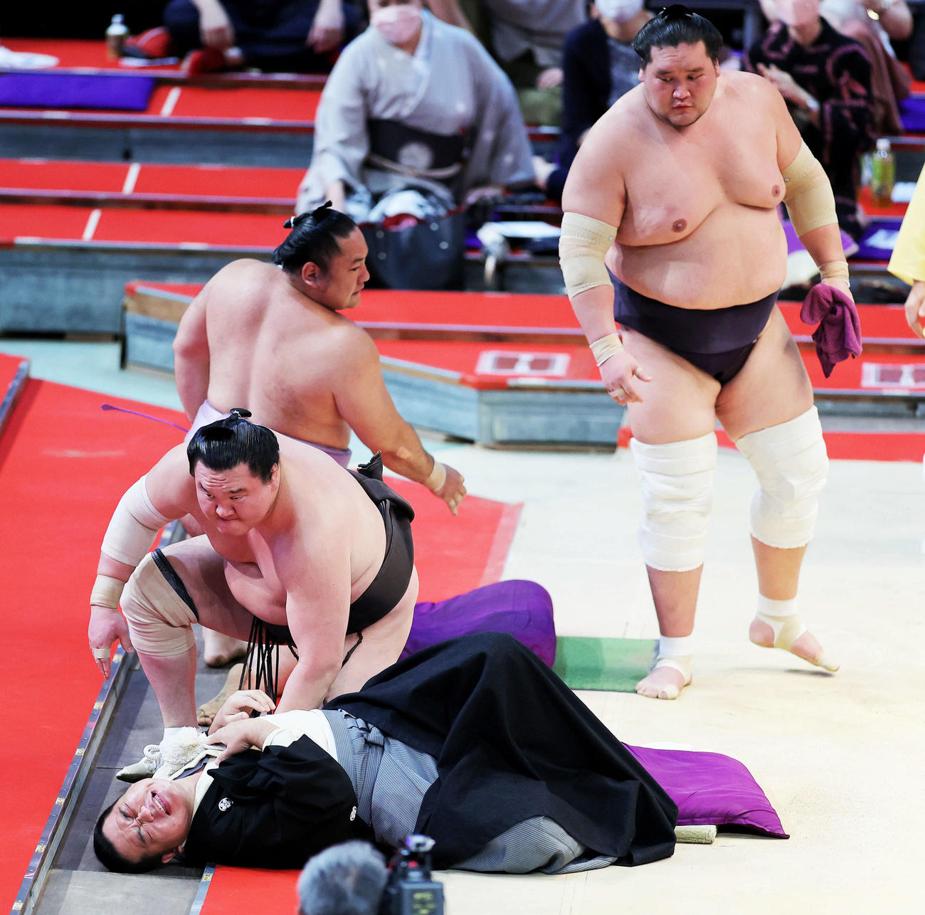 琴恵光（奥）を寄り切りで下した白鵬（中央左）は、勢い余り審判の枝川親方（下）に激しくぶつかる。右は心配そうに見つめる照ノ富士（撮影・河田真司）