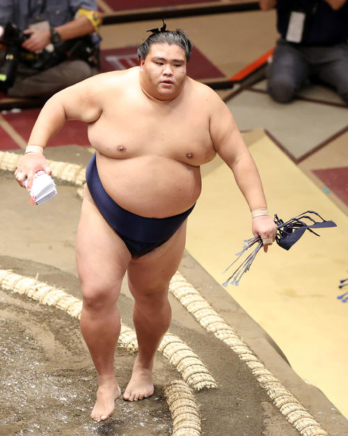懸賞金の束を手に土俵を引き揚げる御嶽海（撮影・鈴木正人）