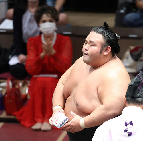 豊昇龍突き落としで破り、懸賞金の束を手に土俵から引き揚げる貴景勝。後方左は拍手するデヴィ夫人（撮影・河田真司）