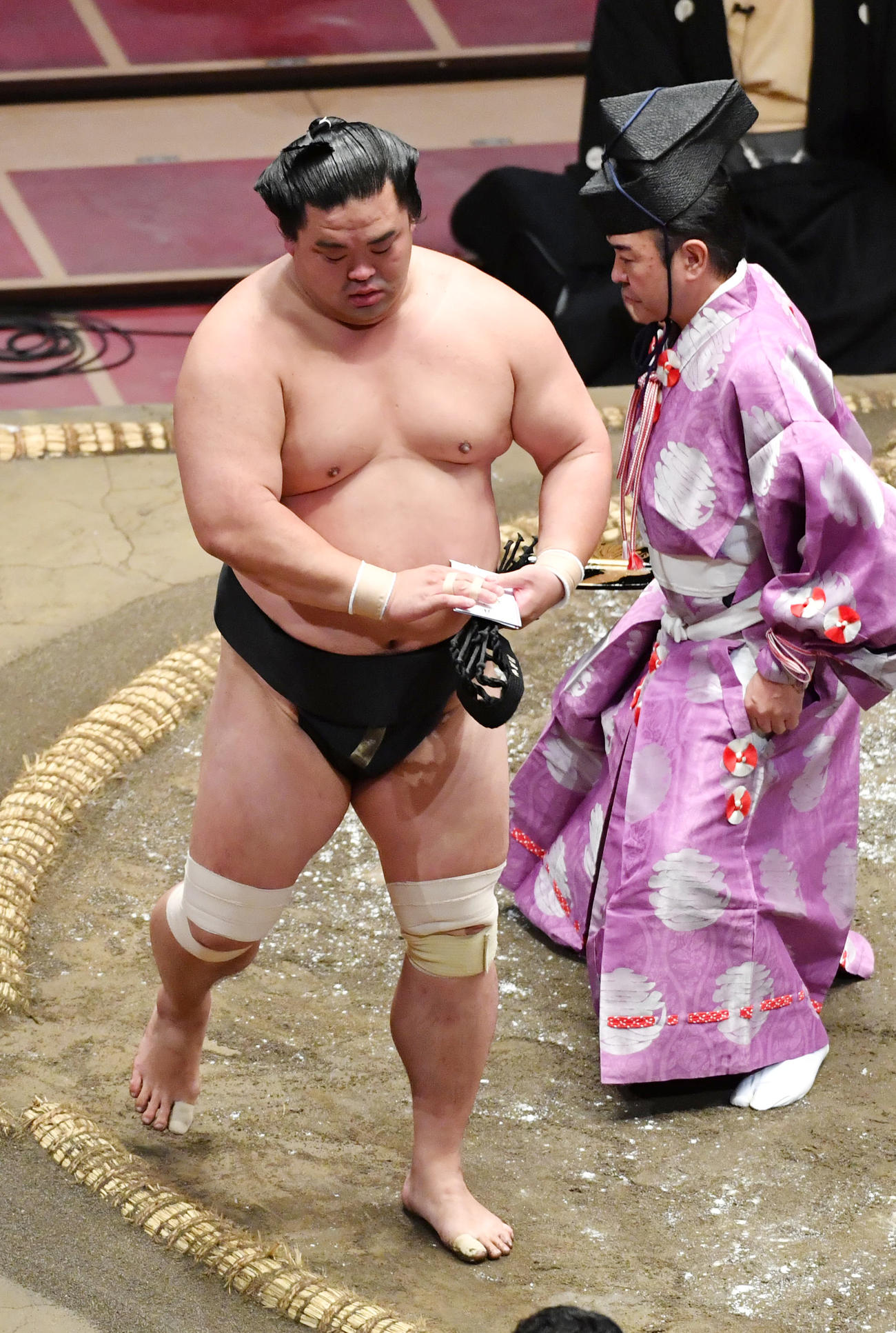 妙義龍は志摩ノ海を寄り切りで破り懸賞を受け取る（撮影・柴田隆二）