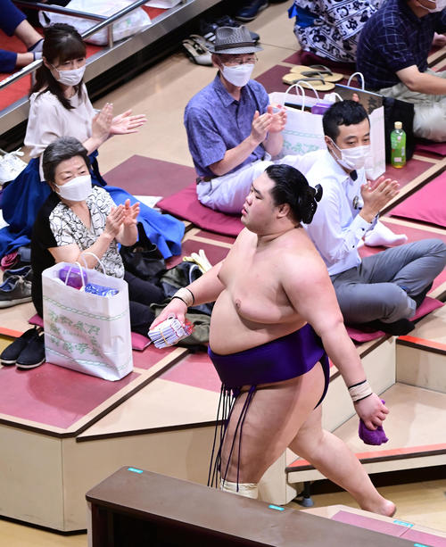 照ノ富士に勝った明生は声援を受けながら懸賞を手に花道を引き揚げる（撮影・小沢裕）