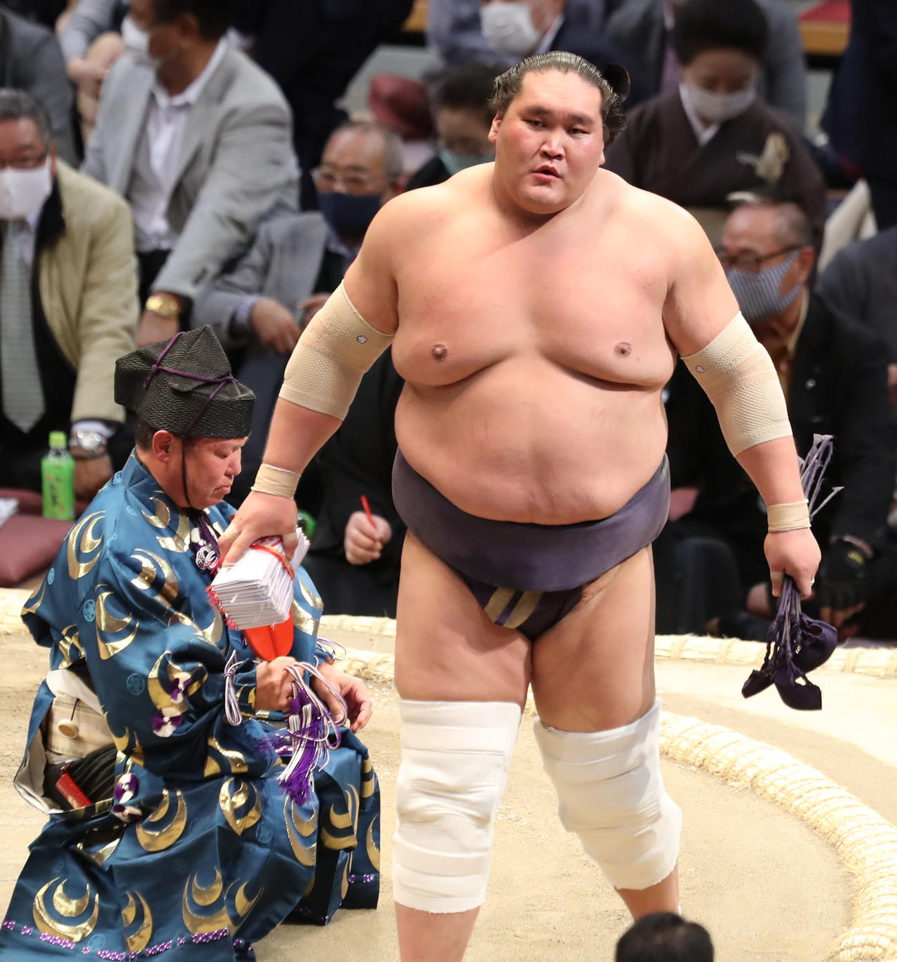 御嶽海（左）を寄り切りで破り、懸賞金を受け取る照ノ富士（撮影・屋方直哉）