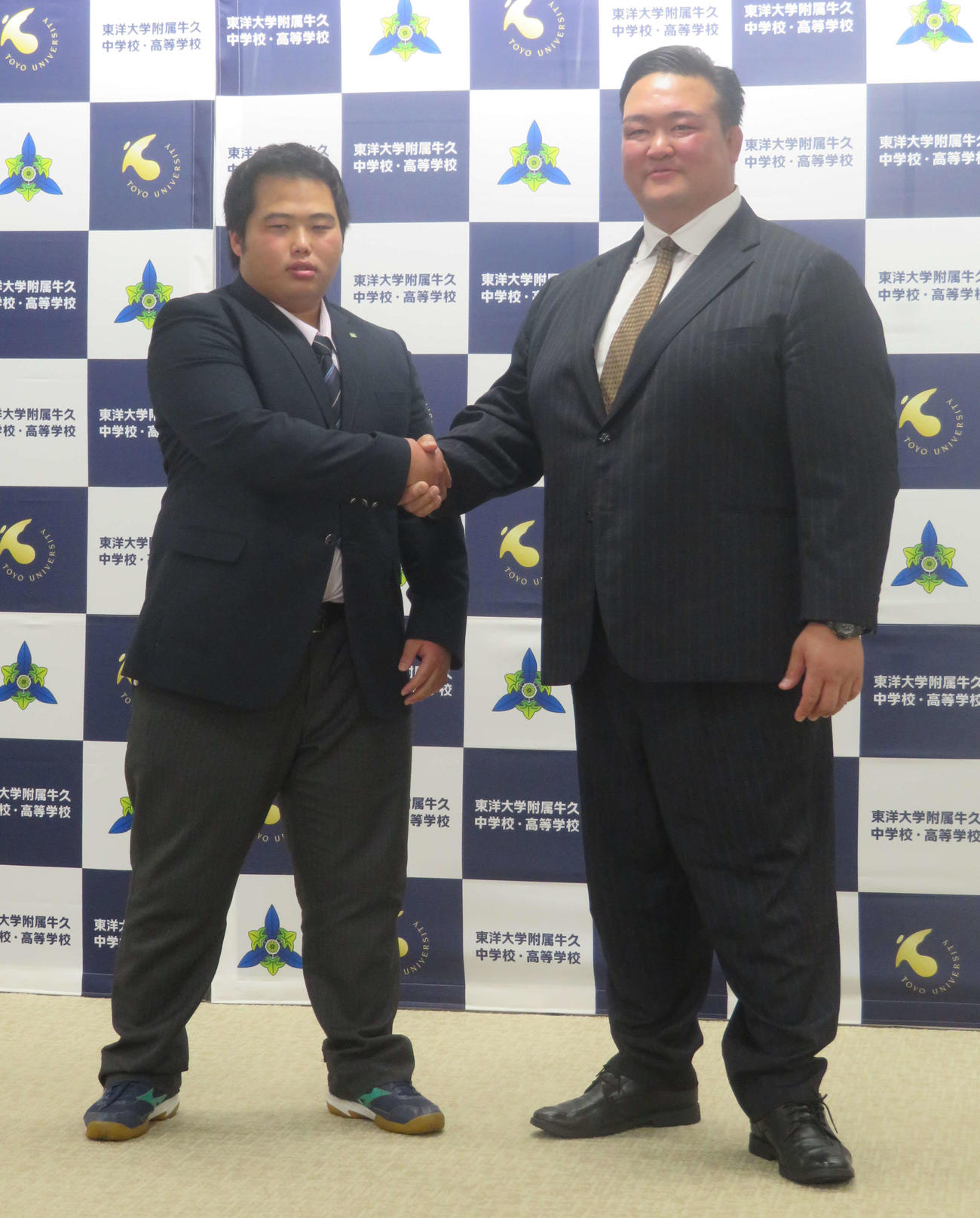 茨城・東洋大牛久高で荒磯部屋入門会見を行った同校3年の花房海（左）と、握手を交わす荒磯親方（撮影・佐藤礼征）