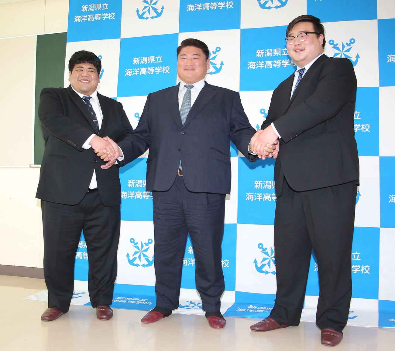 笑顔で握手する3人。左から嘉陽、中村親方、高橋