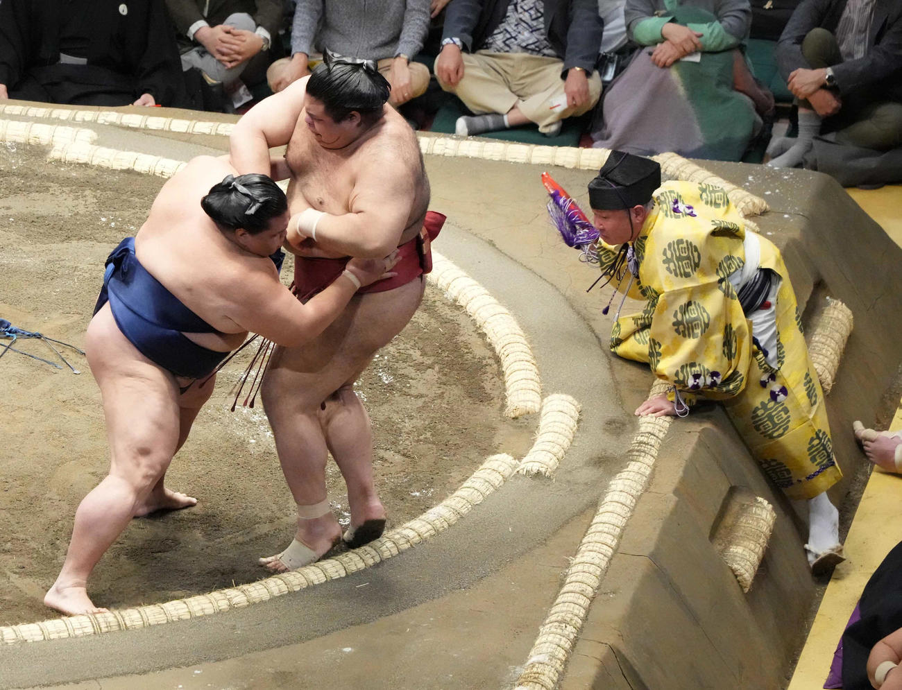 御嶽海（左）は高安を押し出しで破る。右は土俵に懸命に土俵に上がる行司の式守伊之助（撮影・小沢裕）