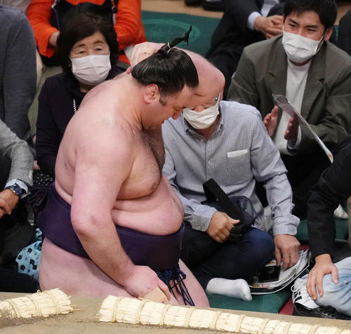 錦木に押し倒しで敗れ土俵から落ちた栃ノ心は、首を押さえる（撮影・菅敏）