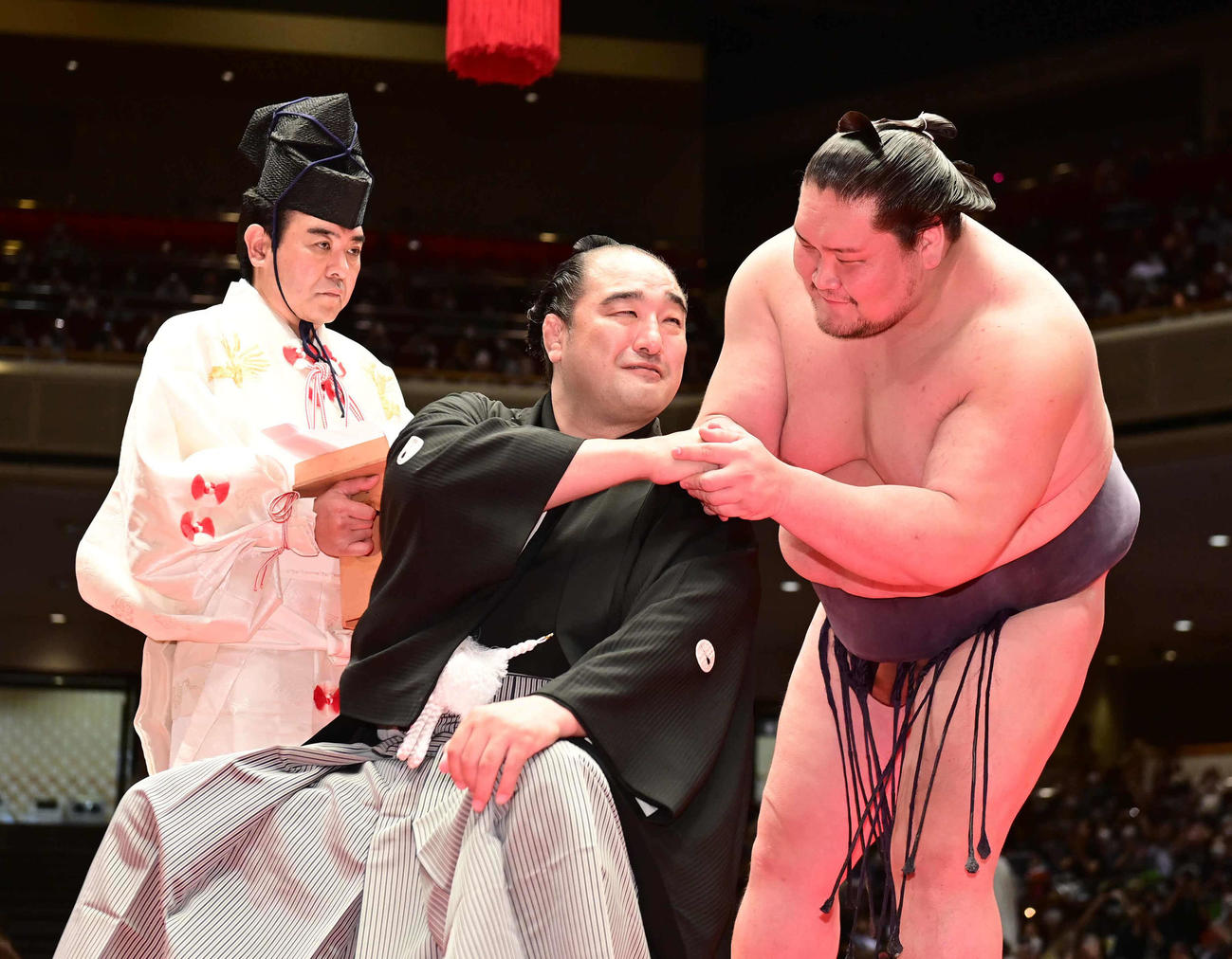 断髪式ではさみを入れてくれた照ノ富士（右）と握手をかわす元安美錦の安治川親方。行司は木村寿之介（撮影・小沢裕）