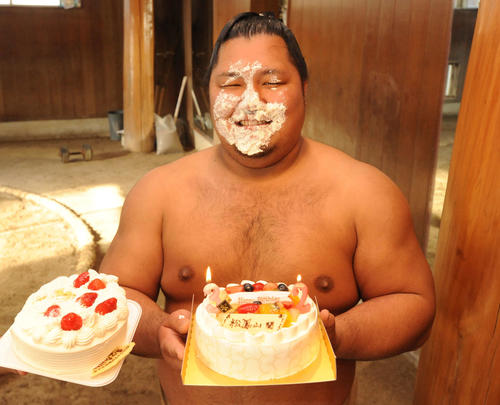 部屋の若い衆と関係者から贈られた誕生日ケーキを手に、クリームまみれで笑顔を見せる松鳳山（2016年2月9日撮影）