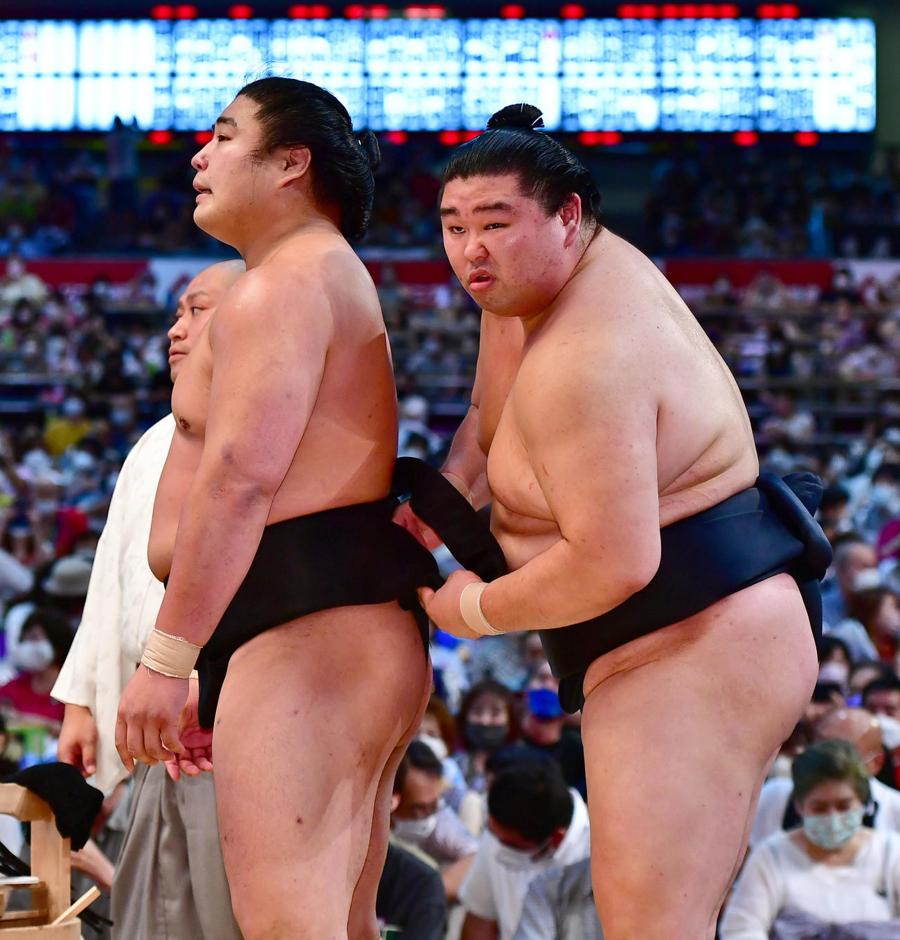 審判団の協議中に控えで正代（右）からまわしを締め直してもらう若元春（撮影・小沢裕）