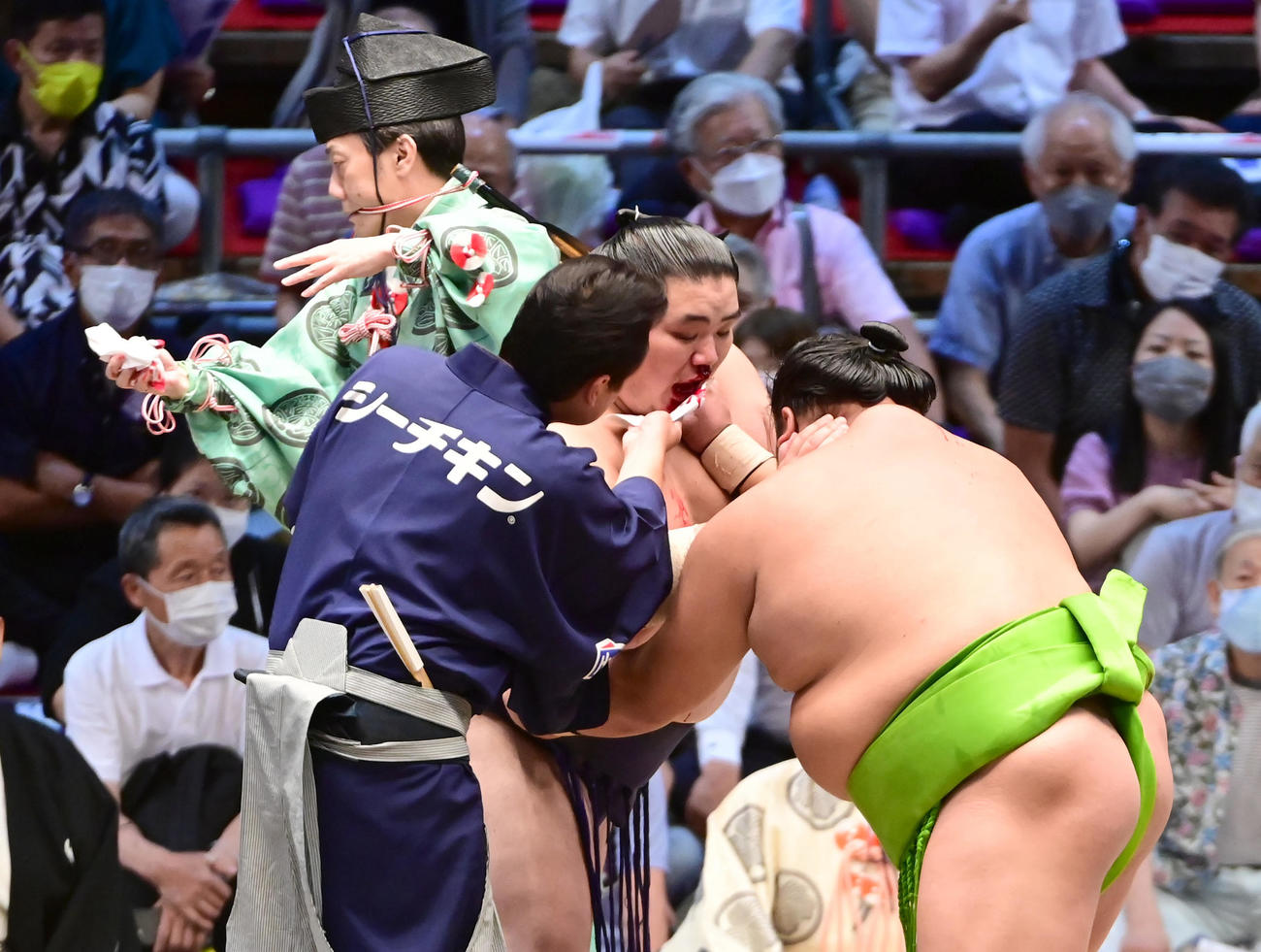 鼻から出血した大翔鵬と天空海の一番に待ったをかけて治療する行司の式守鬼一郎（左奥）と呼出の利樹之丞（撮影・小沢裕）