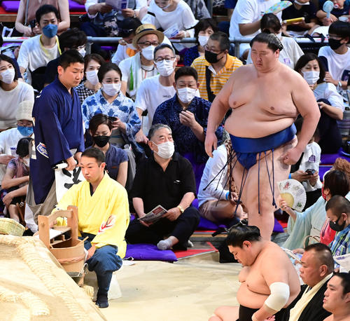 場内に掲げられた不戦勝の旗が呼び出し（左）に片付けられる中、勝ち名乗りを受けるため土俵に現れる逸ノ城（撮影・小沢裕）